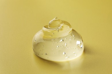 Sample of clear cosmetic gel on yellow background, closeup