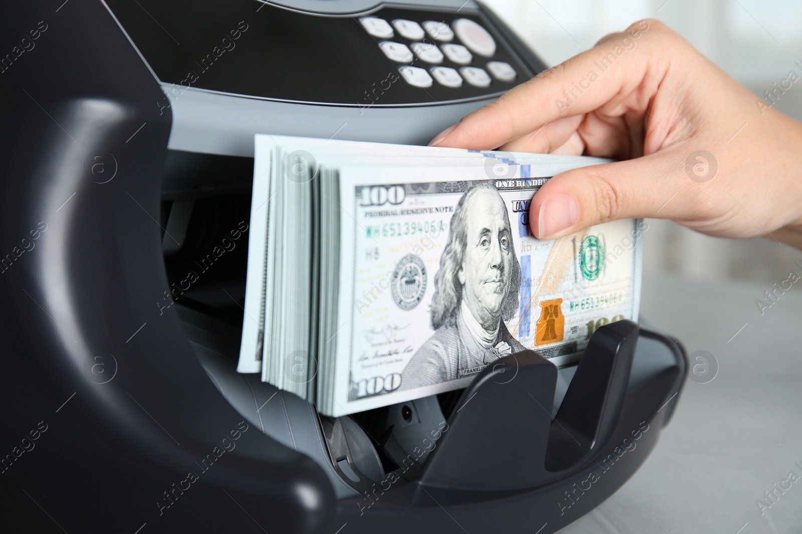 Photo of Woman taking money from counting machine at table indoors, closeup