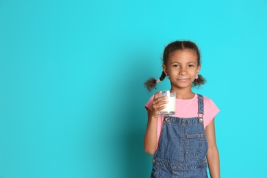 Photo of Adorable African-American girl with glass of milk on color background