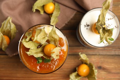 Delicious dessert decorated with physalis fruit on wooden table, flat lay