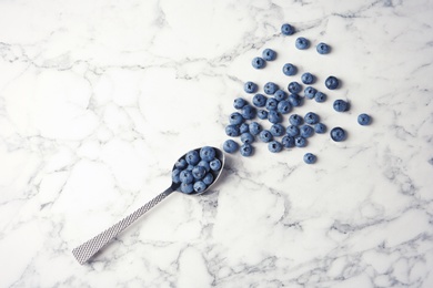 Photo of Flat lay composition with juicy fresh blueberries and space for text on marble table, top view