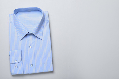 Photo of Stylish light blue shirt on white background, top view with space for text. Dry-cleaning service