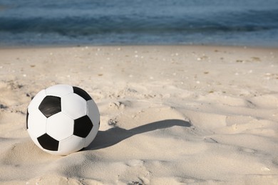 Soccer ball on beach, space for text. Football equipment