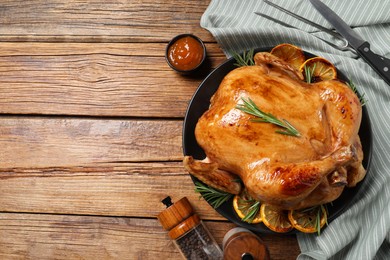 Photo of Tasty roasted chicken with rosemary and lemon served on wooden table, flat lay. Space for text