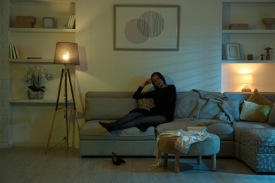 Photo of Woman resting on couch in room at night