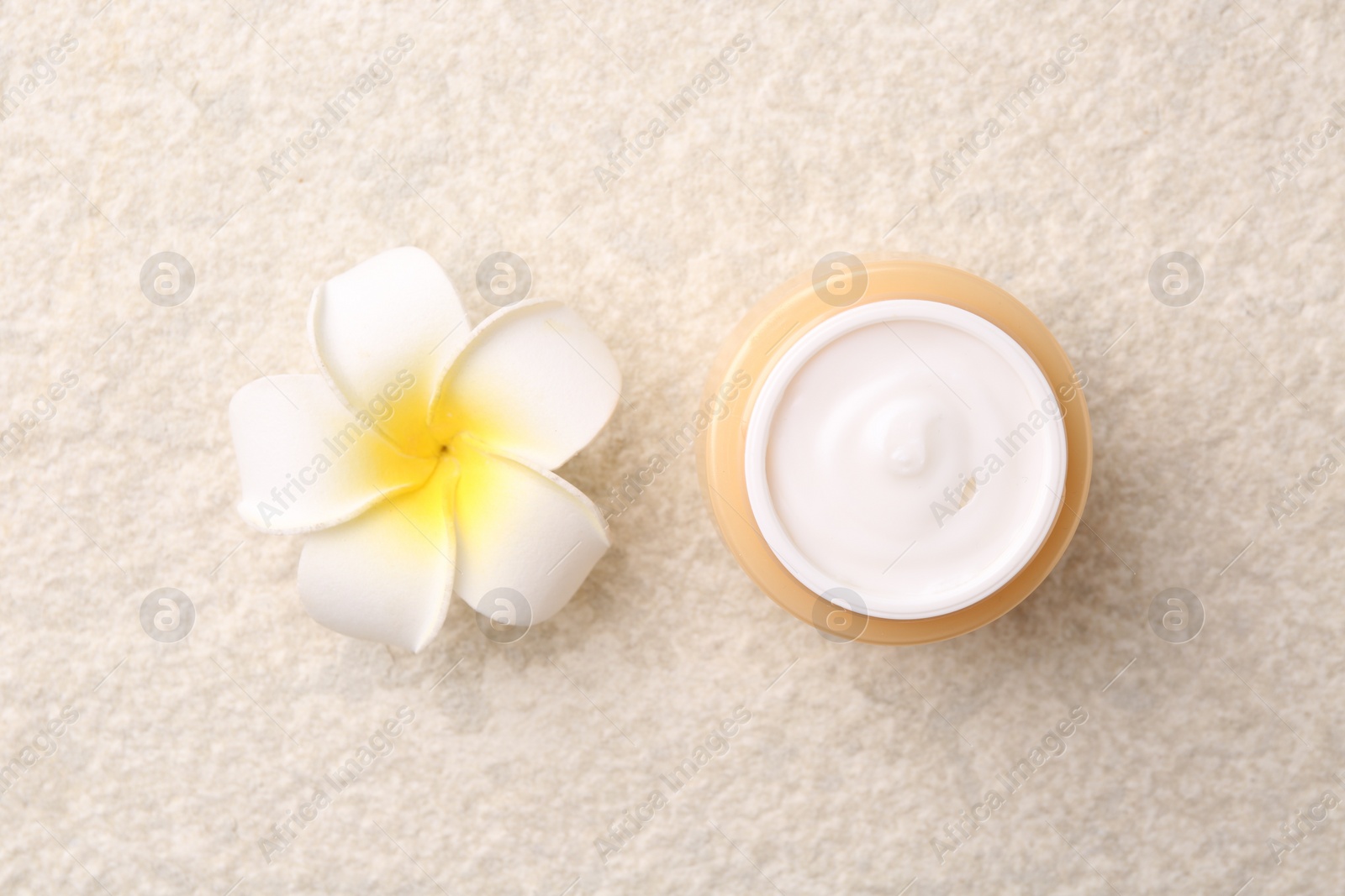 Photo of Body care. Moisturizing cream and flower on light textured table, top view