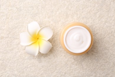 Photo of Body care. Moisturizing cream and flower on light textured table, top view