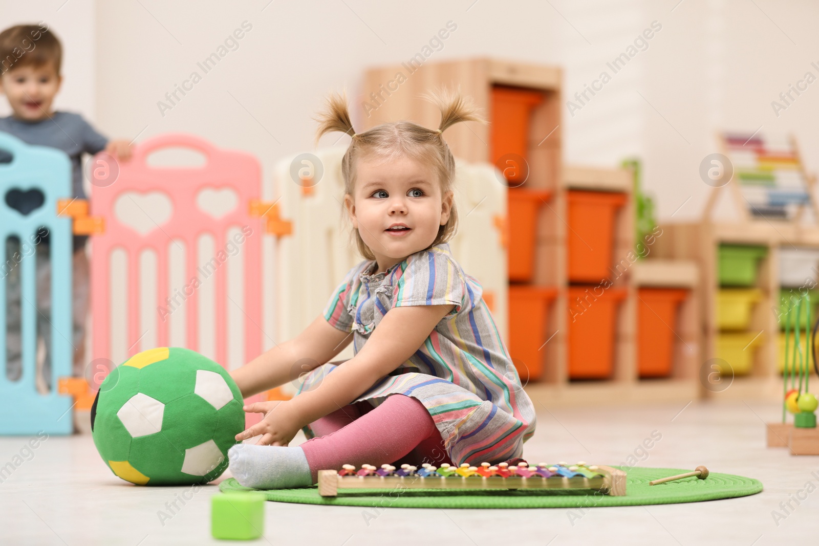 Photo of Cute little child playing with soft ball on floor at home