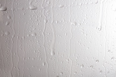 Photo of Glass with rain drops against light background