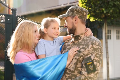 Soldier in military uniform reunited with his family and Ukrainian flag outdoors