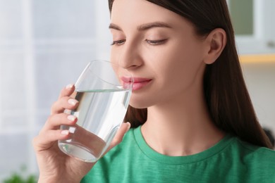 Photo of Healthy habit. Woman drinking fresh water from glass indoors