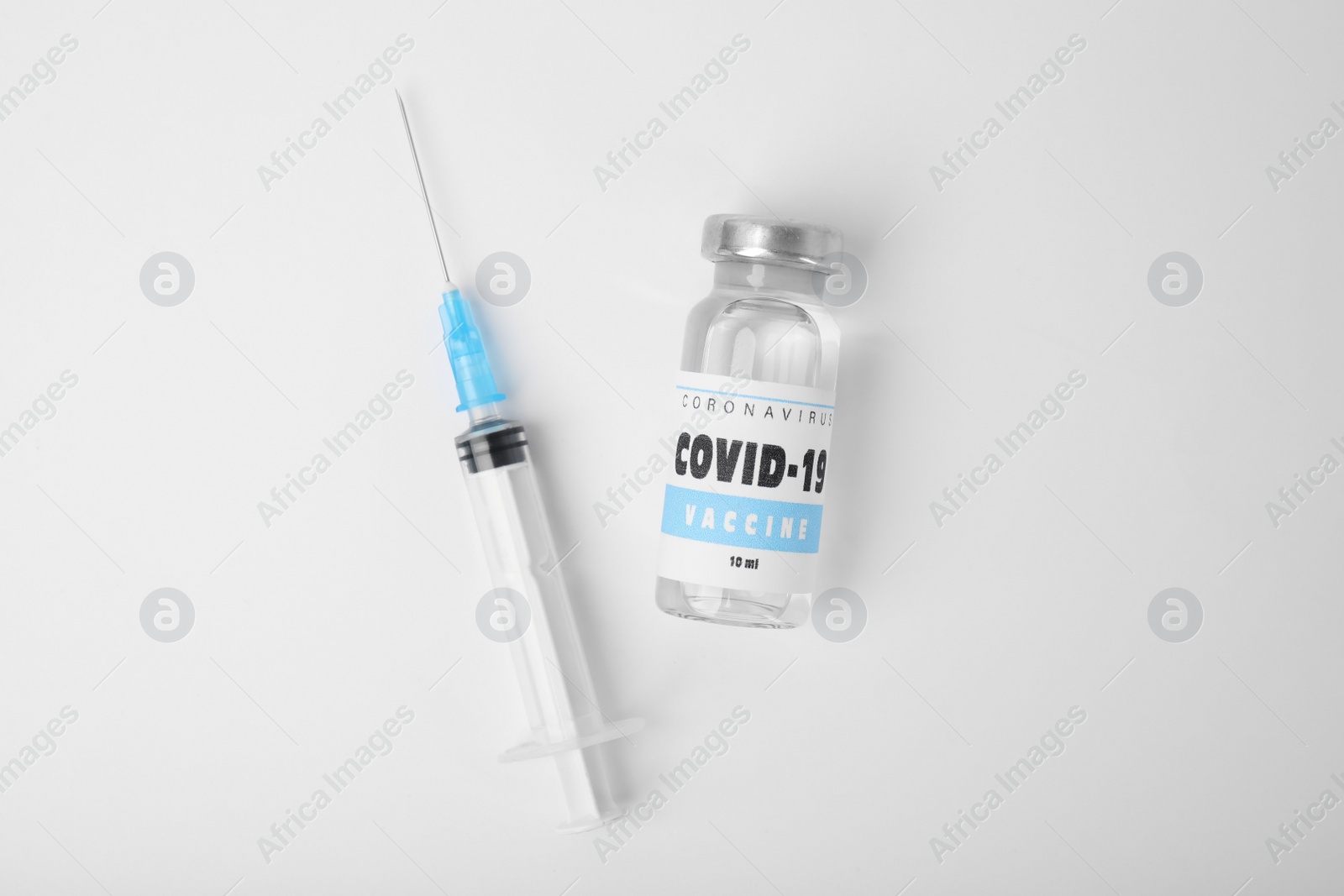 Photo of Vial with coronavirus vaccine and syringe on white background, flat lay