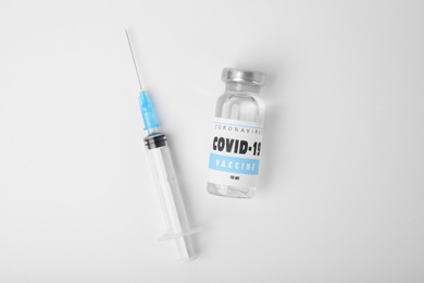 Vial with coronavirus vaccine and syringe on white background, flat lay