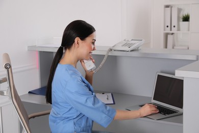 Photo of Receptionist talking on phone at workplace in hospital