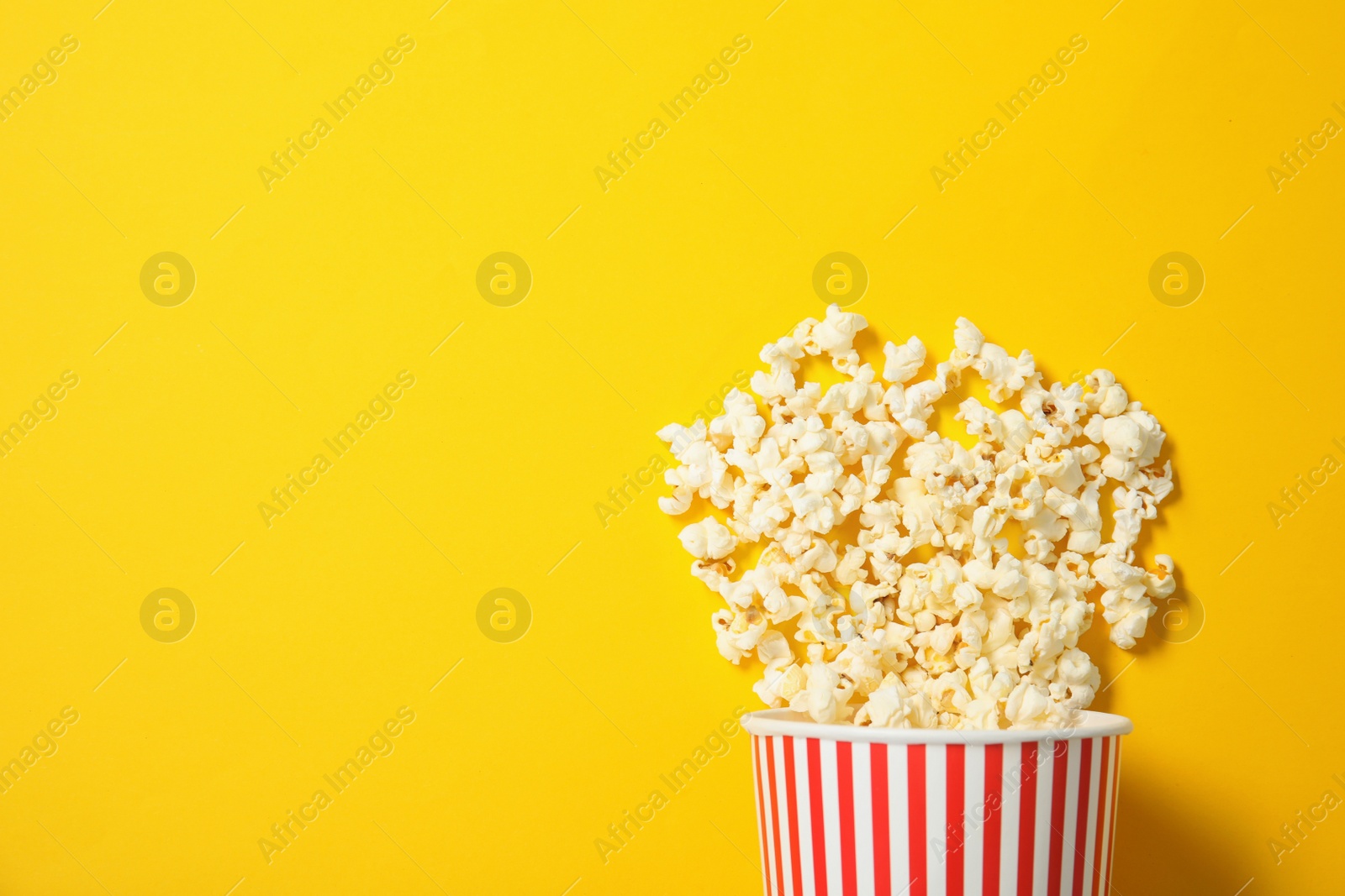 Photo of Fresh tasty popcorn and cup on color background, top view with space for text. Cinema snack