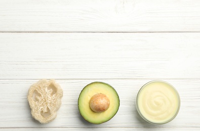 Photo of Handmade face mask, avocado and loofah on white wooden table, flat lay. Space for text