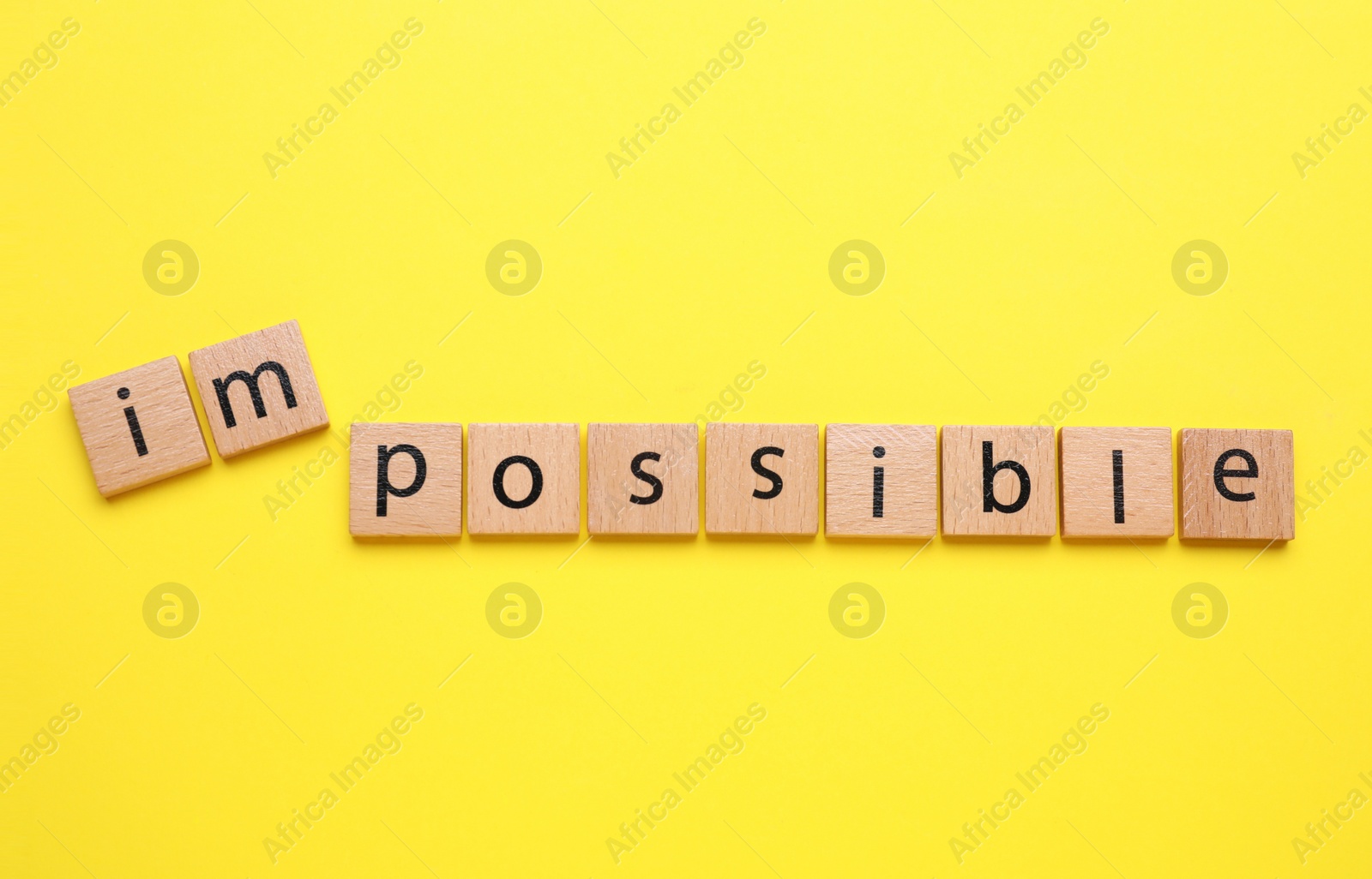 Photo of Motivation concept. Changing word from Impossible into Possible by removing squares with letters I and M on yellow background, top view