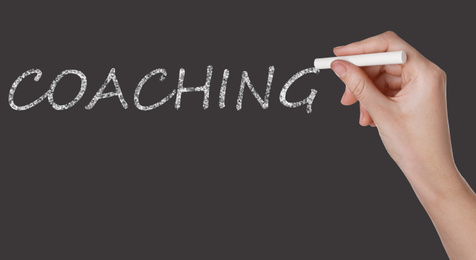 Image of Business or life trainer writing word Coaching on blackboard, closeup. Banner design 