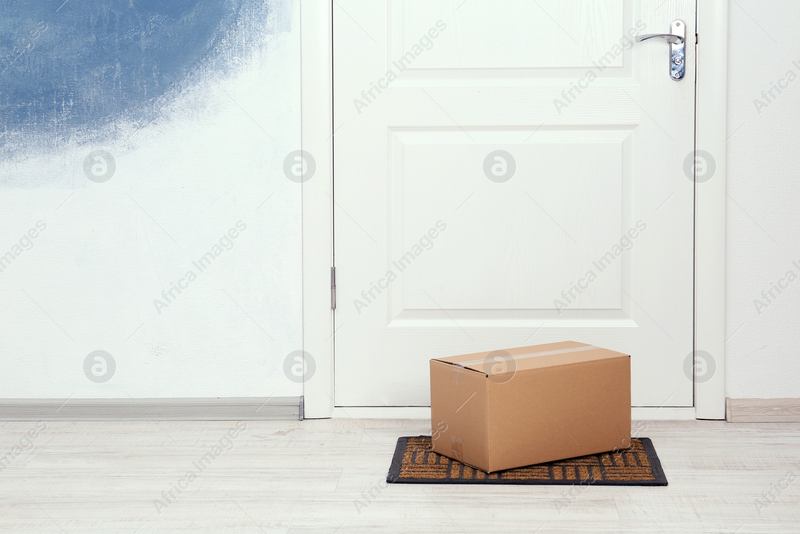 Photo of Cardboard box on floor near apartment entrance. Mockup for design