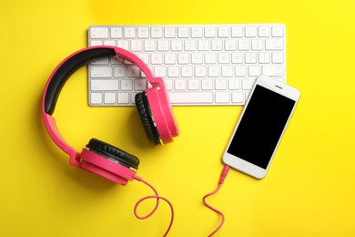 Photo of Modern headphones, phone and keyboard on color background, flat lay. Space for text