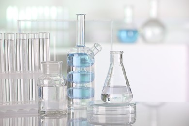Photo of Laboratory analysis. Different glassware with liquid on white table indoors. Space for text