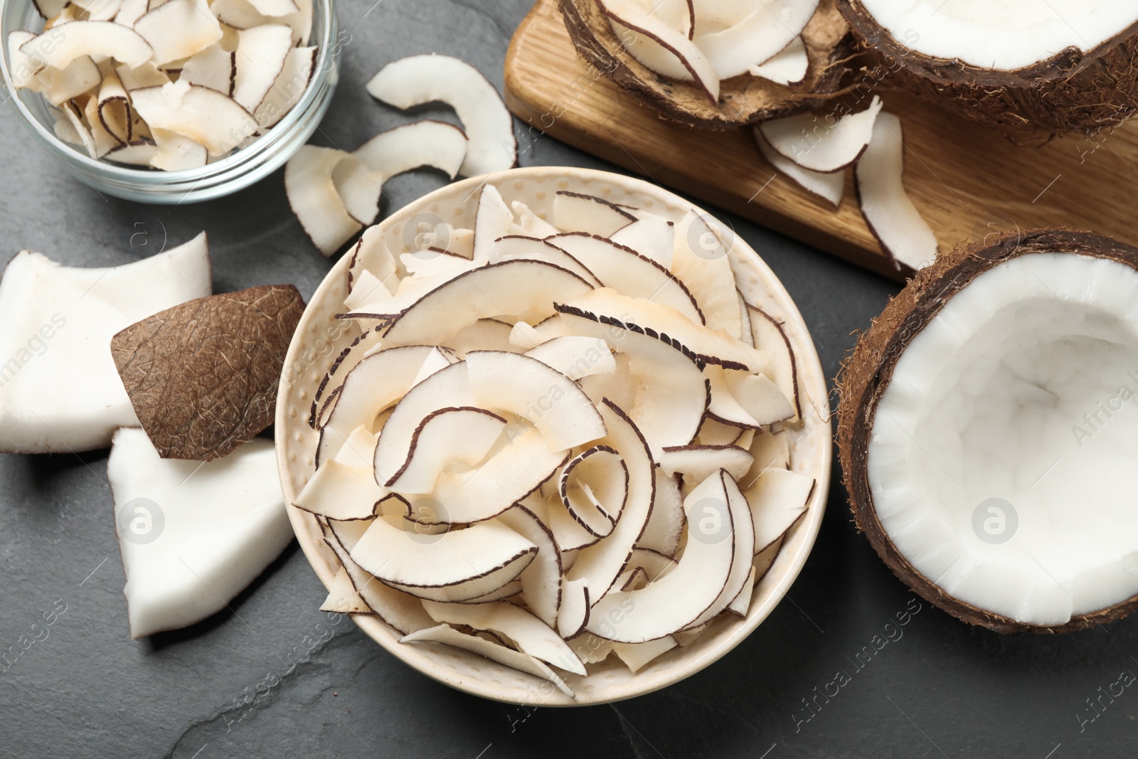 Photo of Flat lay composition with tasty coconut chips on black table