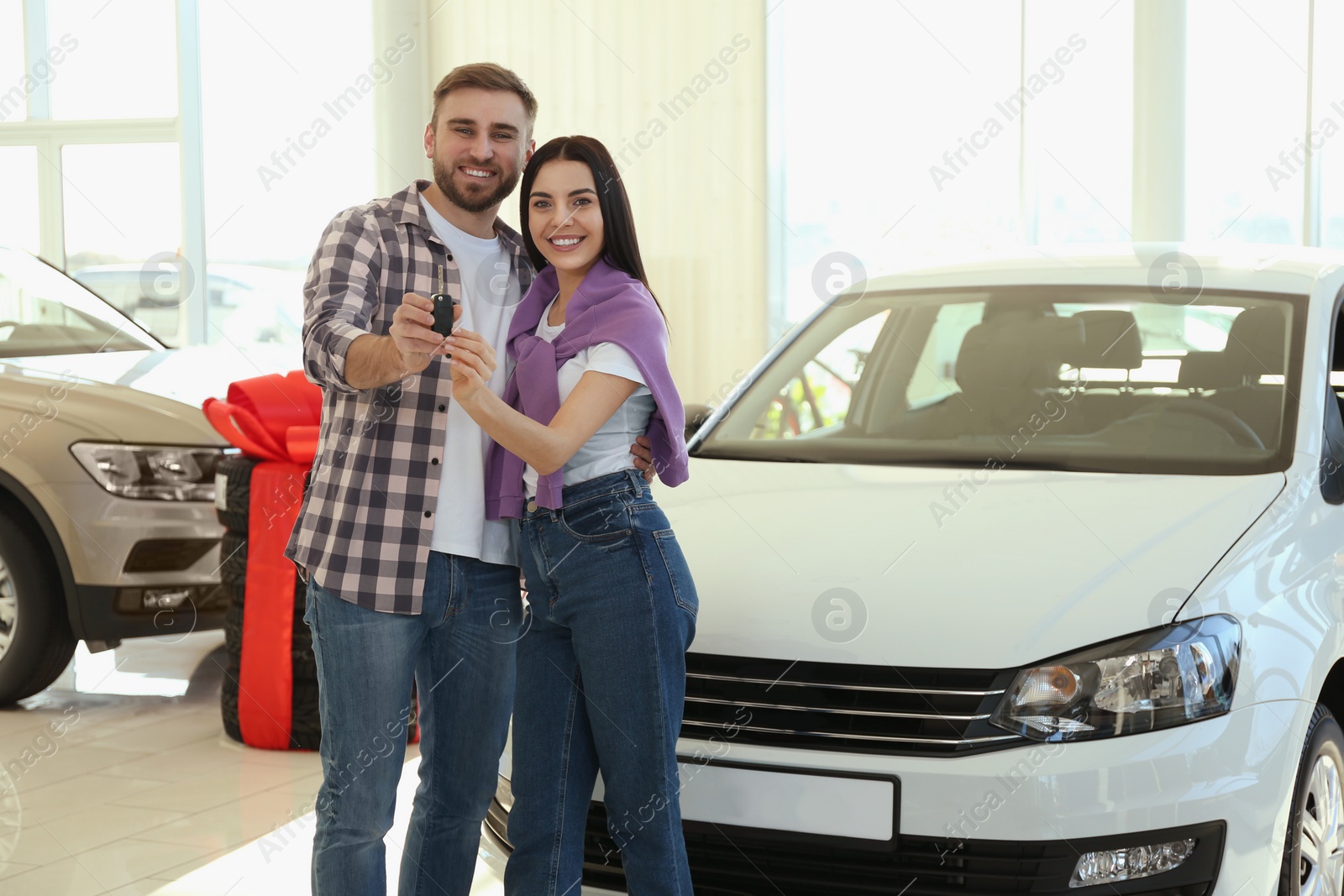 Photo of Happy couple with car key in modern auto dealership