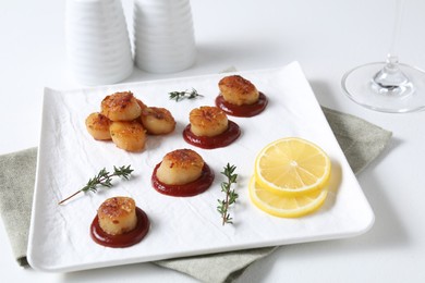 Photo of Delicious fried scallops with tomato sauce and lemon served on white table