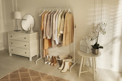 Modern dressing room interior with stylish clothes, shoes and beautiful orchid flowers
