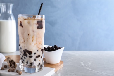 Bubble milk tea with tapioca balls on grey marble table against blue background. Space for text