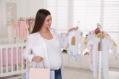 Photo of Happy pregnant woman choosing baby shoes in store. Shopping concept