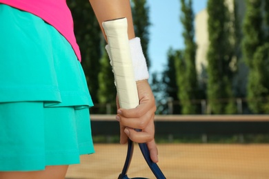 Sportswoman with racket at tennis court on sunny day, closeup