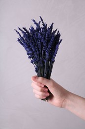 Woman holding bouquet of beautiful preserved lavender flowers on beige background, closeup