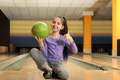 Little girl with ball in bowling club