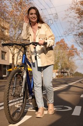 Happy beautiful woman with bicycle on lane in city