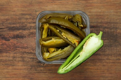 Photo of Fresh and pickled green jalapeno peppers on wooden table, top view