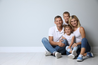 Photo of Happy family with children near grey wall. Space for text
