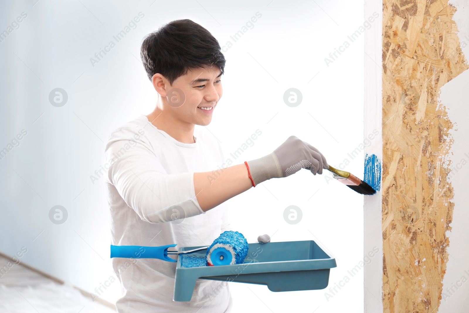 Photo of Male decorator painting wall with brush indoors