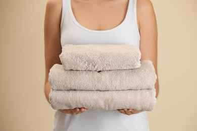 Woman holding fresh towels on beige background, closeup