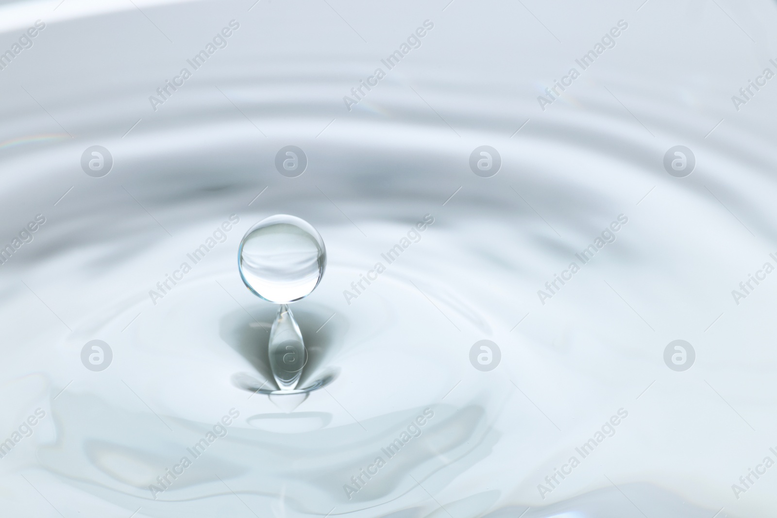 Photo of Splash of clear water with drop on light grey background, closeup