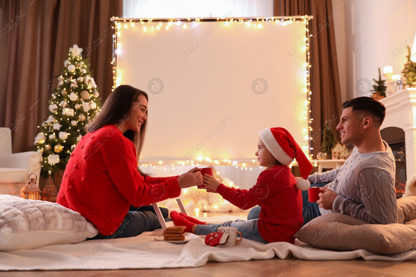 Photo of Family near video projector screen at home. Christmas time