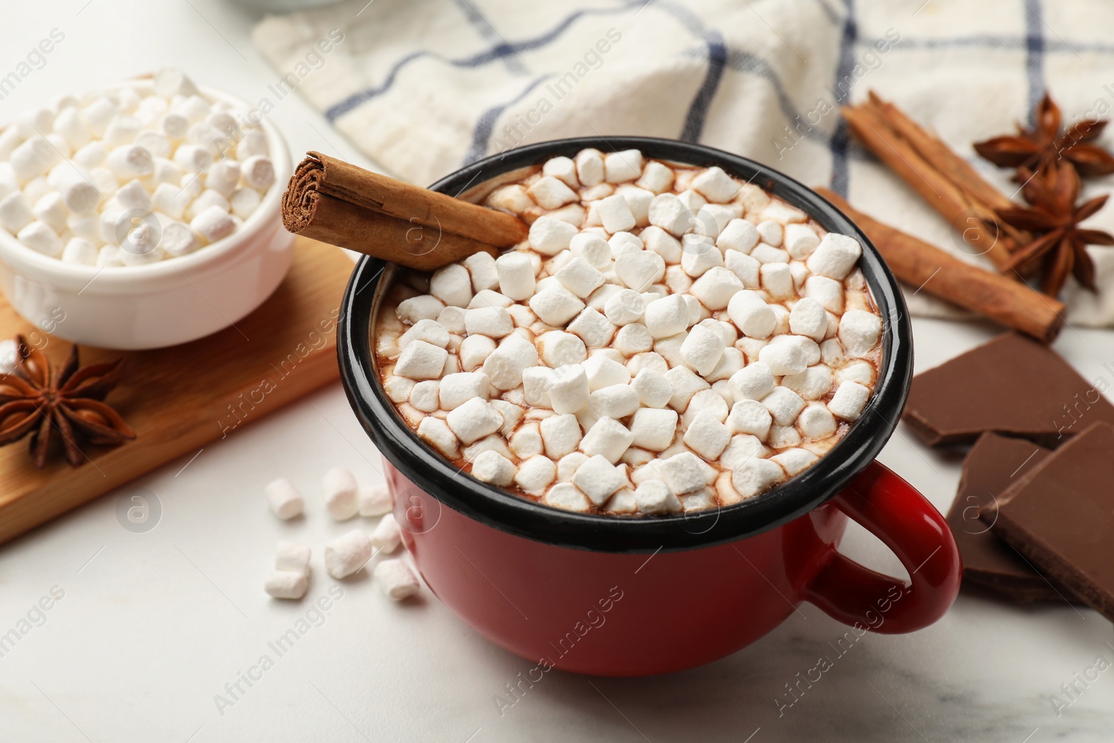 Photo of Tasty hot chocolate with marshmallows and ingredients on white marble table, closeup