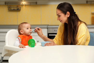 Young mother feeding her little baby at home