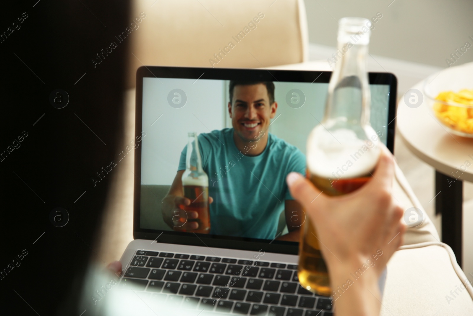 Photo of Friends drinking beer while communicating through online video conference at home. Social distancing during coronavirus pandemic