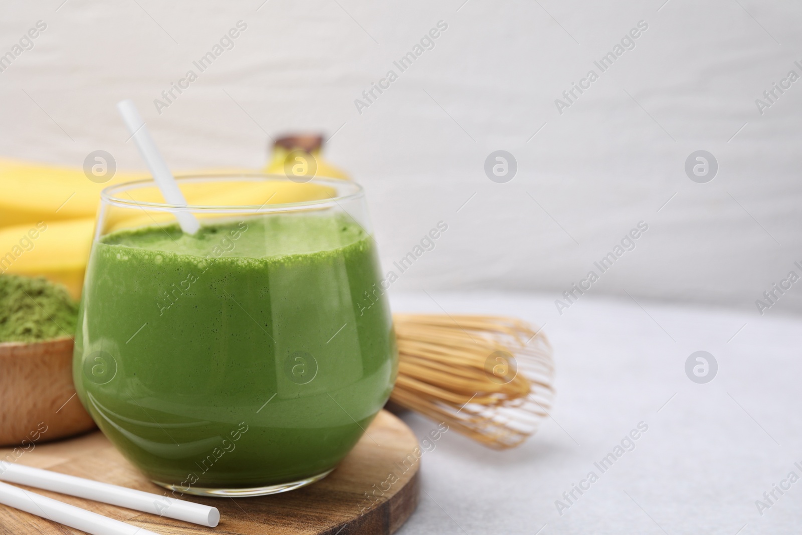 Photo of Glass of tasty matcha smoothie on white table. Space for text