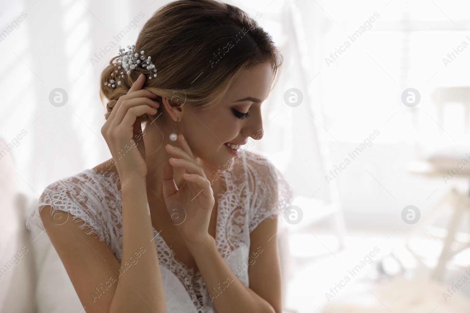 Photo of Young bride with elegant wedding hairstyle in room
