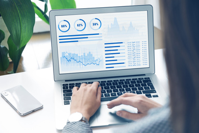 Woman using laptop in office, closeup. Fintech concept