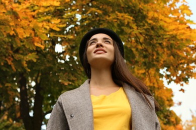 Photo of Young beautiful woman with hat in park, view from below. Autumn walk