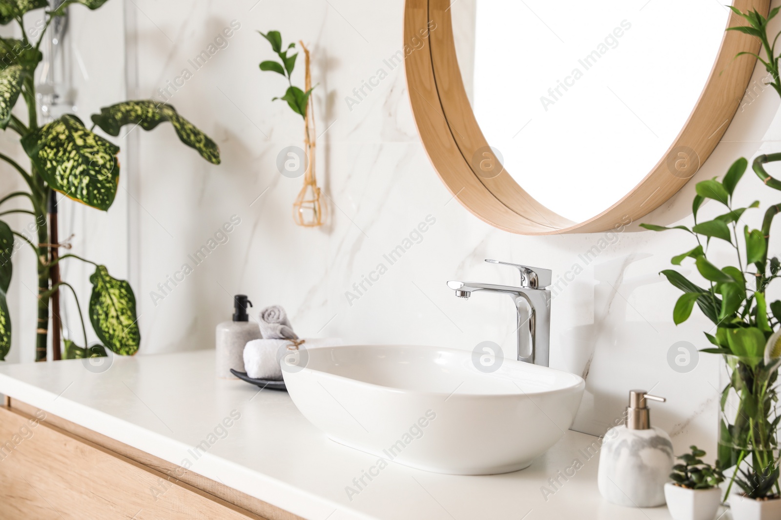 Photo of Stylish vessel sink and green plants in bathroom. Interior design element