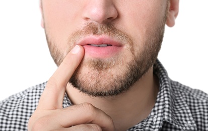 Young man touching lips against white background, closeup